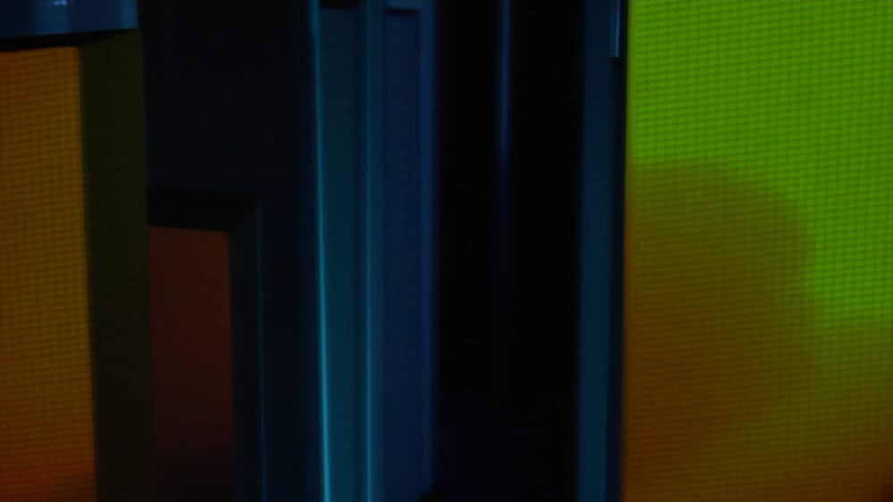 Green-orange projection onto multiple rotating stelae with blue background