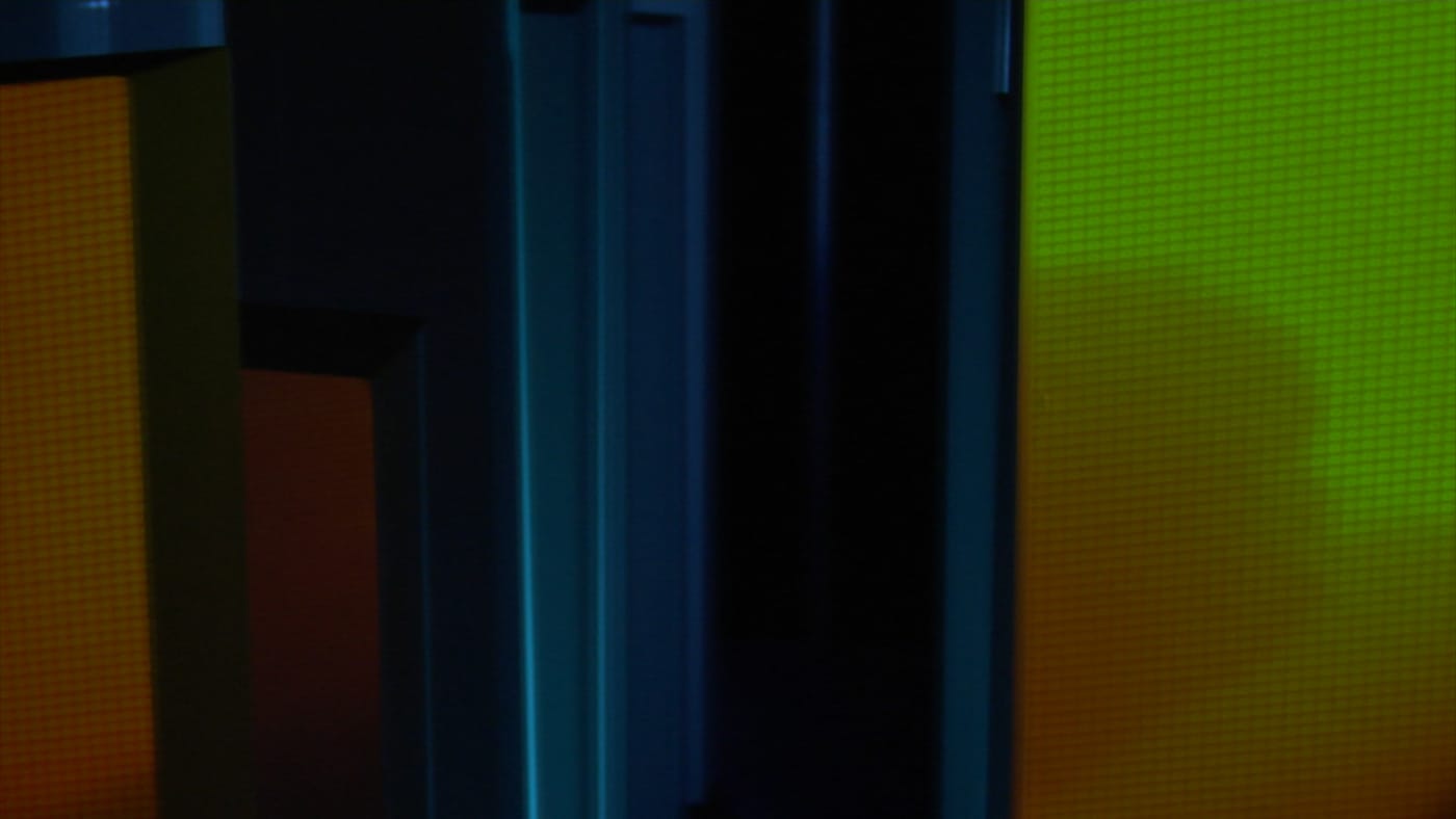 Green-orange projection onto multiple rotating stelae with blue background